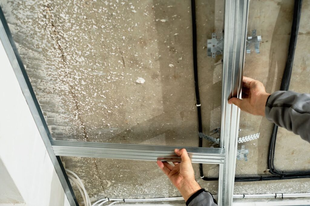 Handwerker richtet ein Metallprofil für eine Trockenbaudecke aus
